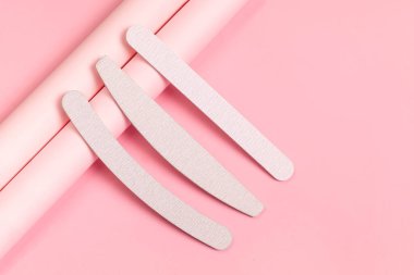 Farklı şekillerde ve sertlikte gri tırnak törpüleri. Pastel pembe arka planda manikür için araçlar. Isometric, modern fotoğraf.
