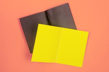 Canlı bir pastel arka plana yerleştirilmiş boş siyah ve sarı defterler, markalaşma ve yaratıcı modeller için mükemmel..