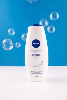 Ukrayna, Kyiv. 19.02.2024. Mavi arka planda sabun köpükleri olan bir şişe duş jeli. Banyo için Nivea ürünleri. 