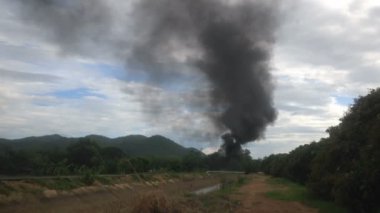 Dark smoke group beside the road with irrigation canal in countryside, air pollution, global warming. Full hd footage.