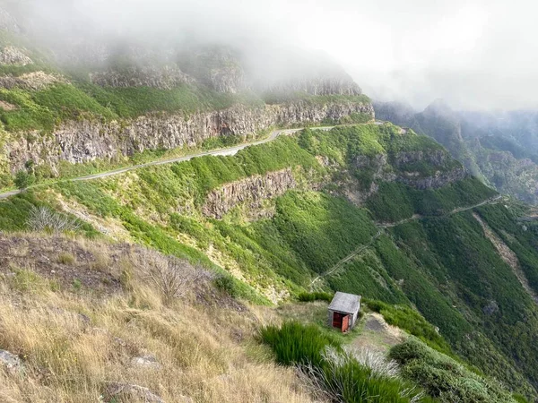 Madeira 'daki tehlikeli dağlar. Yeşil manzaralı bir manzara, yol ve küçük bir kulübe. Panoramik görünüm.