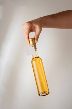 Elinde küçük bir şişe kuru beyaz şarap ya da markasız tatlı likör var. Sahte şablon. Dikey çekim, beyaz arkaplan