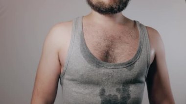 Close up slow motion shoot of strong man in sweaty shirt showing biceps and touching hairy armpits. Refusal of depilation or shaving. Beauty standards, bodypositive, brutal masculinity concept.