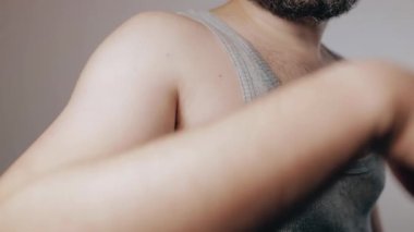 Close up slow motion shoot of man in shirt soaked with sweat from heat touching his hairy armpit. Removal of unwanted hair, using of deodorant or antiperspirant from sweat and smell. Beauty standards, bodypositive concept.