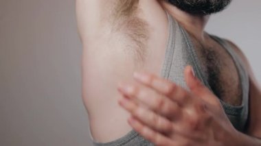 Close up slow motion shoot of sweaty and smelly from heat man touching his hairy armpit. Removal of unwanted hair, using of deodorant or antiperspirant from sweat and smell. Beauty standards, bodypositive concept.