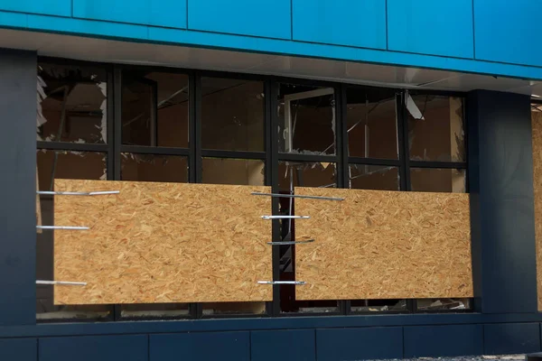 stock image Civil building damaged by military drones attack. Windows with broken glass covered with OSB boards. Repairing after war afthermath