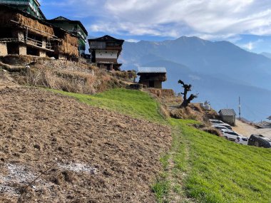 Bu görüntü, görkemli dağlara karşı yan yana dizilmiş kırsal hayatın huzur veren güzelliğini yakalıyor. Doğal ihtişam ve insan yerleşiminin ahenkli bir karışımını resmediyor. Aynı zamanda dağların üzerinde yaşamanın güzelliğinin özünü de yansıtıyor..