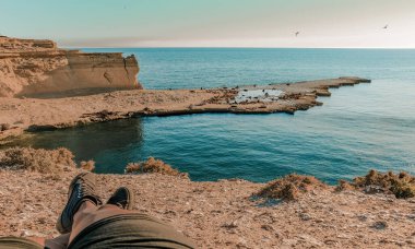 Patagonya Atlantik Yarımadası Valdes, Chubut, Arjantin 'in Patagonya Atlantik kıyısındaki bir uçurumda dinlenen deniz aslanlarının bulunduğu güzel kayalık bir kıyı manzarasının (POV) ilk resmi.