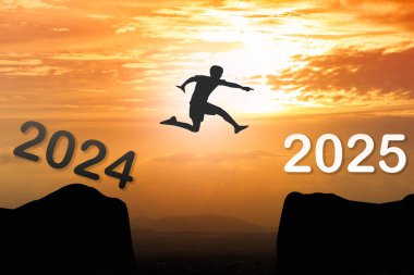 2025 Yeni Yıl Konsepti: Silüet adam 2024 'ten 2025' e atlıyor dağların üzerinden gün batımında güzel altın gökyüzünde