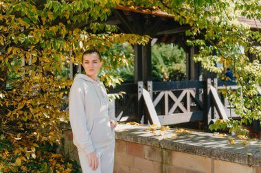 Sonbaharda bir parkta duran zarif bir kadın. Sonbahar sarı yaprakları. Sonbaharda parkta neşeli bir kadının portresi. Sarı yapraklı mutlu kız. Güzel, romantik kız dışarıda eğleniyor.