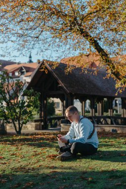 Profesyonel fotoğrafçı güzel bir sonbahar parkının fotoğrafını çekiyor. Profesyonel fotoğrafçı, sonbahar parkında kamerayla oturur.