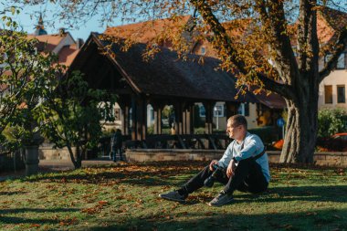 Profesyonel fotoğrafçı güzel bir sonbahar parkının fotoğrafını çekiyor. Profesyonel fotoğrafçı, sonbahar parkında kamerayla oturur.