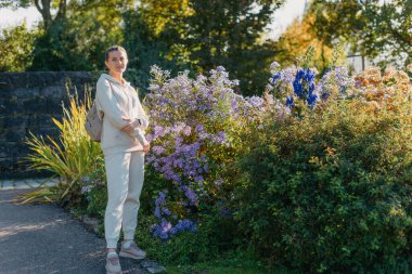 Sonbaharda bir parkta duran zarif bir kadın. Sonbahar sarı yaprakları. Sonbaharda parkta neşeli bir kadının portresi. Sarı yapraklı mutlu kız. Güzel, romantik kız dışarıda eğleniyor.