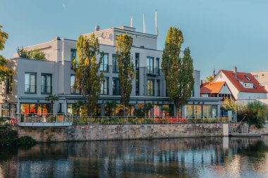 Gün batımında nehir. Kasaba binaları ve rıhtımdaki çok katlı evler. River 'da günbatımı. Banliyö evleri ve Avrupa 'da nehir kenarındaki yerleşim yerleri. Doğada ev gün batımında kıyıda.