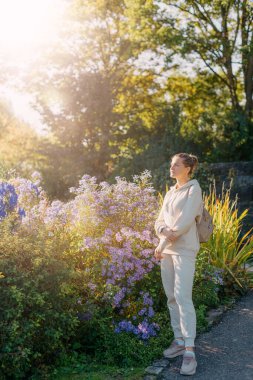 Sonbaharda bir parkta duran zarif bir kadın. Sonbahar sarı yaprakları. Sonbaharda parkta neşeli bir kadının portresi. Sarı yapraklı mutlu kız. Güzel, romantik kız dışarıda eğleniyor.