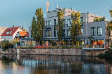 Gün batımında nehir. Kasaba binaları ve rıhtımdaki çok katlı evler. River 'da günbatımı. Banliyö evleri ve Avrupa 'da nehir kenarındaki yerleşim yerleri. Doğada ev gün batımında kıyıda.