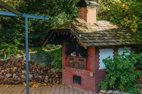 村のヤードでそれのための古いストーブと薪 秋に古い石の暖炉の屋外 ヨーロッパでパンを焼くための木材と伝統的なレンガオーブン — ストック写真
