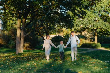 Bir aile annesi ve iki oğlu parkta koşup zıplıyorlar. Oğullar, çocuklar, anne, koşun, oynayın, sevinin, yazın doğanın tadını çıkarın. Aile takım çalışması. Sahada birlikte koşan mutlu aile takımı.