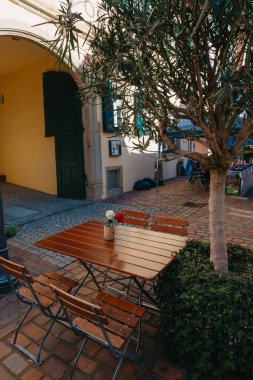 Beyaz masa ve sandalyeli boş bir kafe terası. Kafe restoranının dışında. Sokağın iç tarafındaki kafe. Çiçekleri ve Fransız tarzı kafe masası olan rahat bir cadde. Bisikletli bir kafenin ön cephesi. Tablo