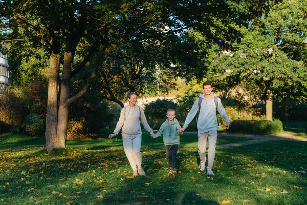Bir aile annesi ve iki oğlu parkta koşup zıplıyorlar. Oğullar, çocuklar, anne, koşun, oynayın, sevinin, yazın doğanın tadını çıkarın. Aile takım çalışması. Sahada birlikte koşan mutlu aile takımı.