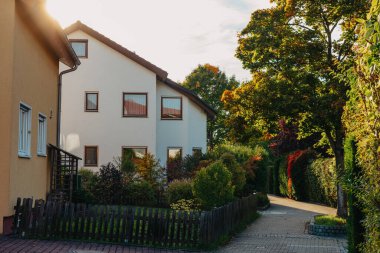Old white cottage in cozy town. Street view landscape old city, little houses on sunset. Old architecture street front view. Calm old town street. Stone white pink rural cottages and summer gardens.
