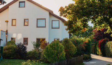 Old white cottage in cozy town. Street view landscape old city, little houses on sunset. Old architecture street front view. Calm old town street. Stone white pink rural cottages and summer gardens.