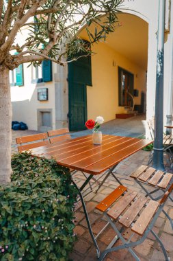 Beyaz masa ve sandalyeli boş bir kafe terası. Kafe restoranının dışında. Sokağın iç tarafındaki kafe. Çiçekleri ve Fransız tarzı kafe masası olan rahat bir cadde. Bisikletli bir kafenin ön cephesi. Tablo