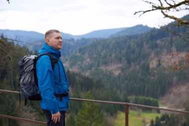 Sırt çantalı bir turist dağ yolunda dikiliyor ve uzaklığa bakıyor. Seyahat ve macera kavramı. Sırt çantalı gezgin dağ gezgini yaşam tarzı konsept dağları