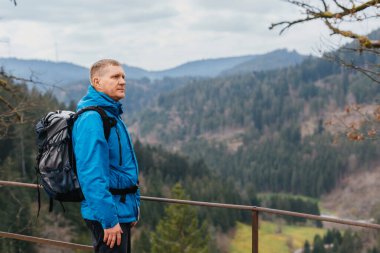 Sırt çantalı bir turist dağ yolunda dikiliyor ve uzaklığa bakıyor. Seyahat ve macera kavramı. Sırt çantalı gezgin dağ gezgini yaşam tarzı konsept dağları
