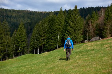 Sırt çantalı bir turist dağ yolunda dikiliyor ve uzaklığa bakıyor. Seyahat ve macera kavramı. Sırt çantalı gezgin dağ gezgini yaşam tarzı konsept dağları