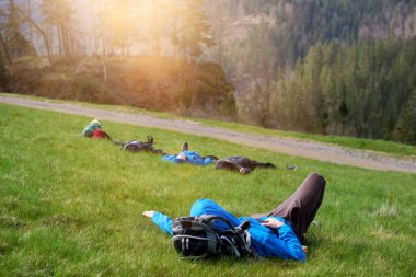 Yürüyüşçüler dağın zirvesinde uzun bir yürüyüşten sonra dinlenmek için uzanırlar. Turist dağın tepesinde yatar ve manzarayı görür.
