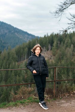 Dağ vadisinde seyahat eden genç ve çekici bir kız yolcunun portresi. Dağın tepesinde poz veren mutlu bir turist. Seyahat ve tatil konsepti. Yürüyüş yolu.