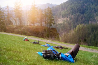 Yürüyüşçüler dağın zirvesinde uzun bir yürüyüşten sonra dinlenmek için uzanırlar. Turist dağın tepesinde yatar ve manzarayı görür.
