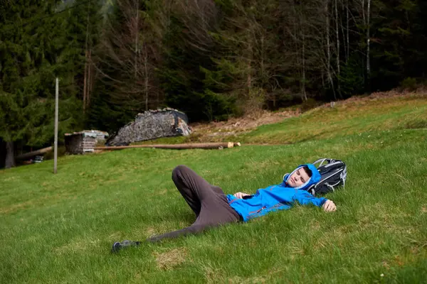 高い山の上に横たわるとリラックスした青の休憩に疲れハイカー 高い山の谷に草の上に横たわるハイカー — ストック写真