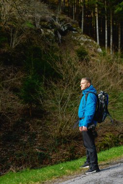Günbatımı dağlarında ağır sırt çantasıyla yürüyüş yapan bir adam. Seyahat tarzı seyahat, macera dolu yaz tatili kavramı. Açık havada tek başına. Tek başına seyahat eden hippi gezgin.