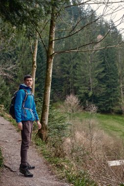 Sırt çantalı bir turist dağ yolunda dikiliyor ve uzaklığa bakıyor. Seyahat ve macera kavramı. Sırt çantalı gezgin dağ gezgini yaşam tarzı konsept dağları