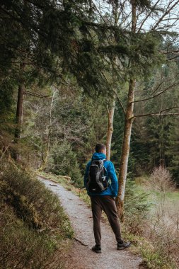 Sırt çantalı bir turist dağ yolunda dikiliyor ve uzaklığa bakıyor. Seyahat ve macera kavramı. Sırt çantalı gezgin dağ gezgini yaşam tarzı konsept dağları