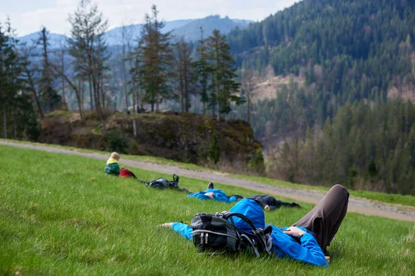 疲惫的徒步旅行者躺在高山顶上休息 远足者躺在高山谷地的草地上 — 图库照片