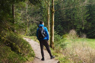 Sırt çantalı bir turist dağ yolunda dikiliyor ve uzaklığa bakıyor. Seyahat ve macera kavramı. Sırt çantalı gezgin dağ gezgini yaşam tarzı konsept dağları