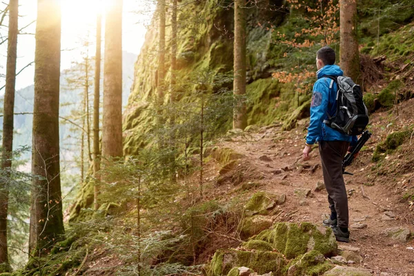 バックパック付きの男の観光客が山道に立って 距離を見ています 旅と冒険の概念 バックパック登山を持つ旅行者の男 トラベルライフスタイルコンセプト山 — ストック写真