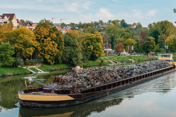 Transportation industry. Ship barge transports scrap metal and sand with gravel. Barge loaded with scrap metal is on the roadstead. Scrap metal transportation by water. Barge laden by metal salvage