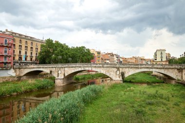 Renkli sarı ve turuncu evler ve Pont de Sant Agusti köprüsü Girona, Katalonya, İspanya 'daki Onyar su nehrine yansıdı. Arka planda Sant Feliu Kilisesi ve Saint Mary Katedrali. 