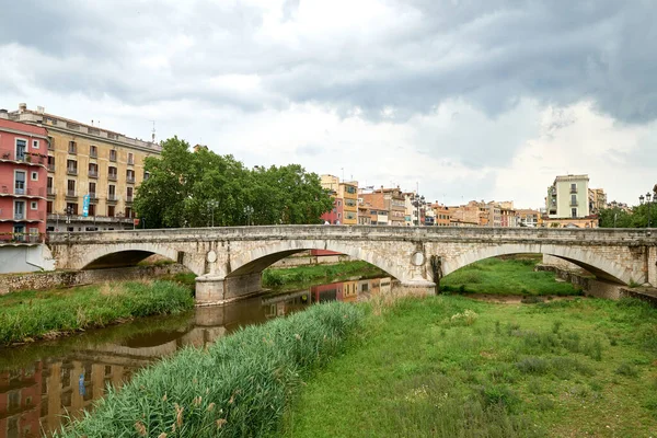 Renkli sarı ve turuncu evler ve Pont de Sant Agusti köprüsü Girona, Katalonya, İspanya 'daki Onyar su nehrine yansıdı. Arka planda Sant Feliu Kilisesi ve Saint Mary Katedrali. 