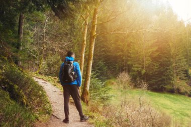 Sırt çantalı bir turist dağ yolunda dikiliyor ve uzaklığa bakıyor. Seyahat ve macera kavramı. Sırt çantalı gezgin dağ gezgini yaşam tarzı konsept dağları