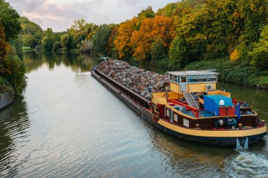 Ulaşım endüstrisi. Gemi mavnası hurda metal ve çakıllı kum taşıyor. Hurda metalle dolu bir mavna yol kenarında. Suyla taşınan metal hurdaları. Metal enkazı yüklü bir mavna.