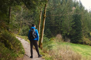 Sırt çantalı bir turist dağ yolunda dikiliyor ve uzaklığa bakıyor. Seyahat ve macera kavramı. Sırt çantalı gezgin dağ gezgini yaşam tarzı konsept dağları