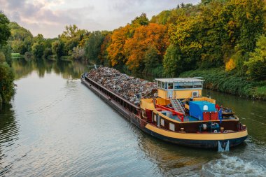 Ulaşım endüstrisi. Gemi mavnası hurda metal ve çakıllı kum taşıyor. Hurda metalle dolu bir mavna yol kenarında. Suyla taşınan metal hurdaları. Metal enkazı yüklü bir mavna.