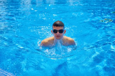 Yüzme havuzunda iyi bir yüzücü eğitimi. Havuza atlayan, ok şeklinde bir şey oluşturan ve arkasında iz bırakan bir adamın tepeden görünüşü. Yüzme havuzunda profesyonel erkek yüzücü. Genç