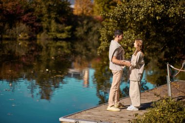 Sahilde, dışarıda sırtında bir kızı taşıyan bir adam. Nehir. Genç aşıklar. Yakışıklı genç adam nehir kenarında kız arkadaşını öpüyor..