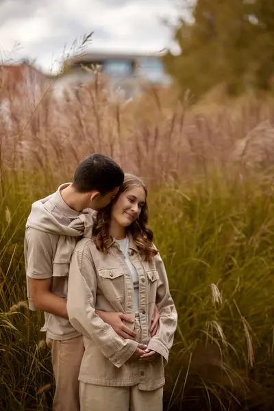Happy couple on autumn walk outdoors. Two lovers in autumn park. Love and tender touch. Gentle hugs. Young man and woman in classic autumn colors outfit on a romantic date in a park. Young girl and